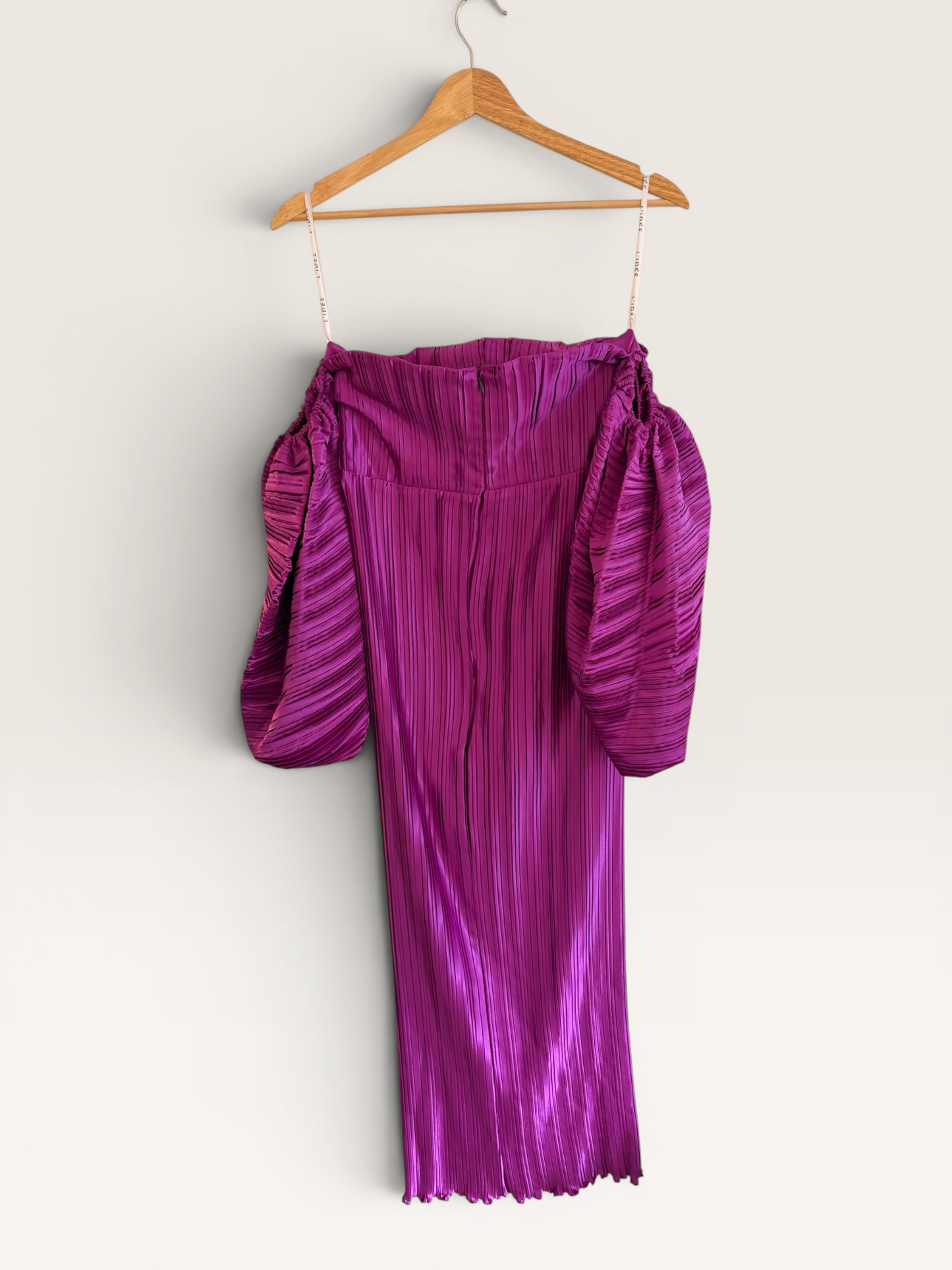The Runway Reserve magenta pleated midi dress with off-the-shoulder neckline and voluminous puff sleeves on a hanger.