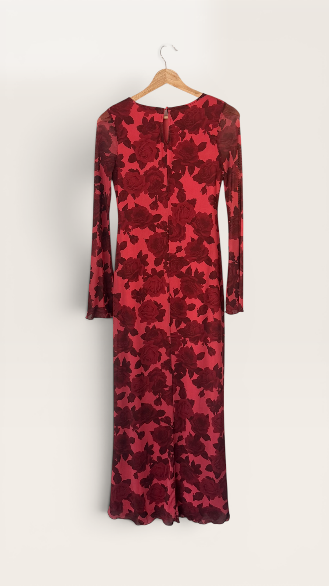 The Runway Reserve red floral mesh long sleeve maxi dress with crew neck hanging on a door.